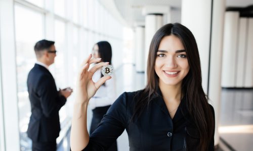 Blockchain and investment concept. Business woman leader holding bitcoin in front of his discussing team on office.